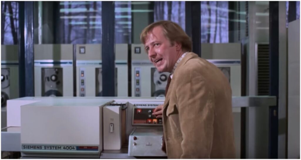 Screenshot aus dem Film Charlie und die Schokoladenfabrik von 1971. Ein Mann steht an einer Siemens 4004, sieht dabei aggressiv aus.